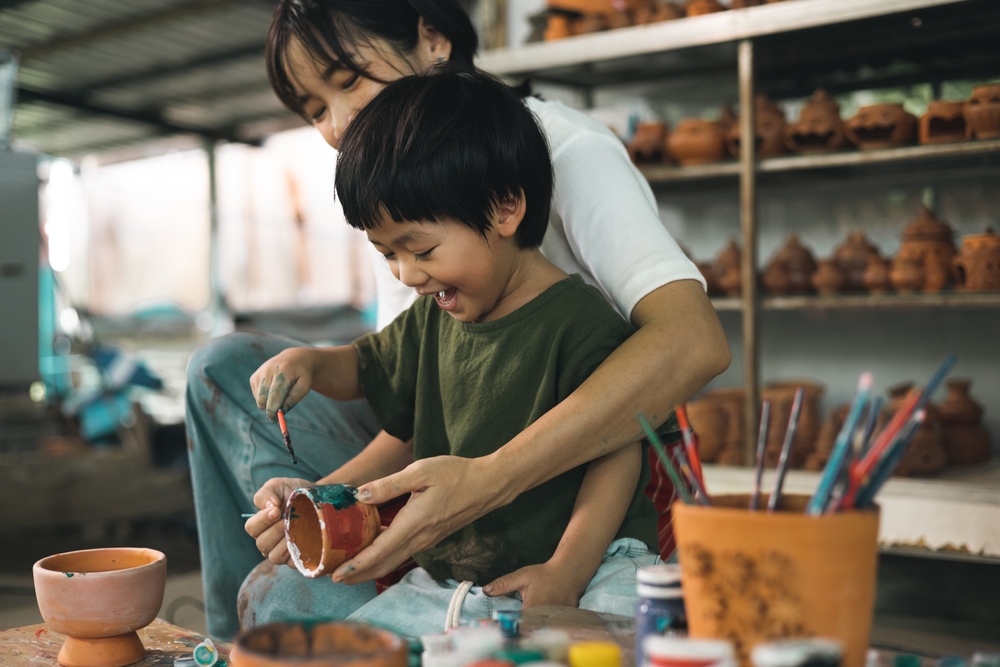A woman and child glaze a ceramic cup in a pottery studio.
