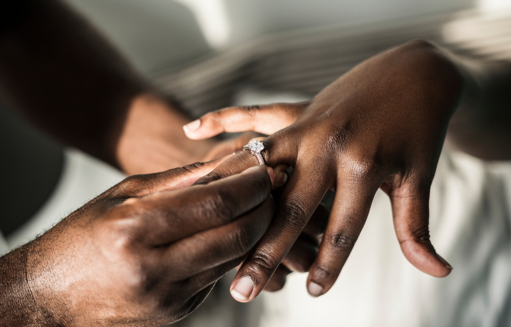 A wedding ring being placed on a woman's finger to symbolize the triumph of love.