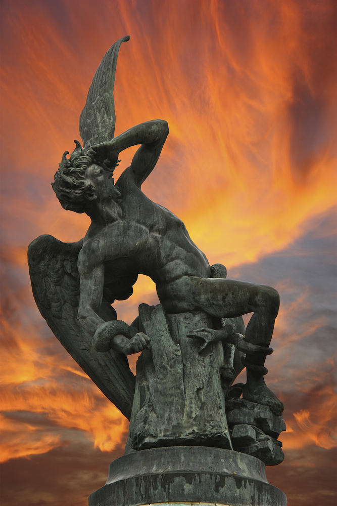 The Fountain of the Fallen Angel sculpture in Madrid, depicting a winged figure in a dramatic struggle against serpents, set before a fiery sky, symbolizing themes of spiritual warfare and the conflict between good and evil in the spiritual realm.