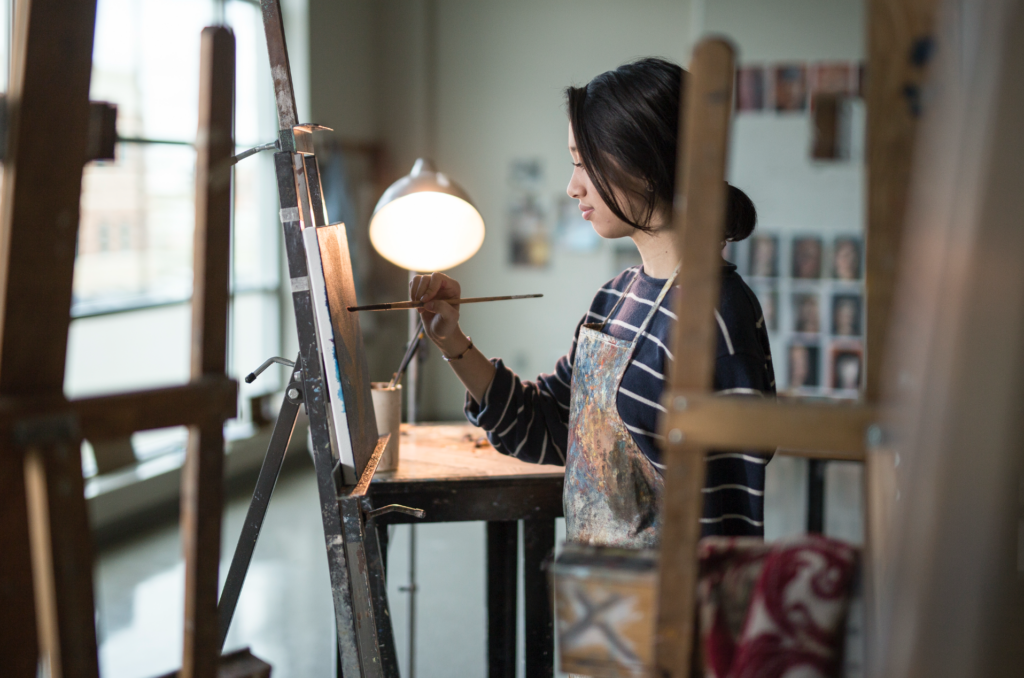 a modern-day female artist painting a portrait in her studio